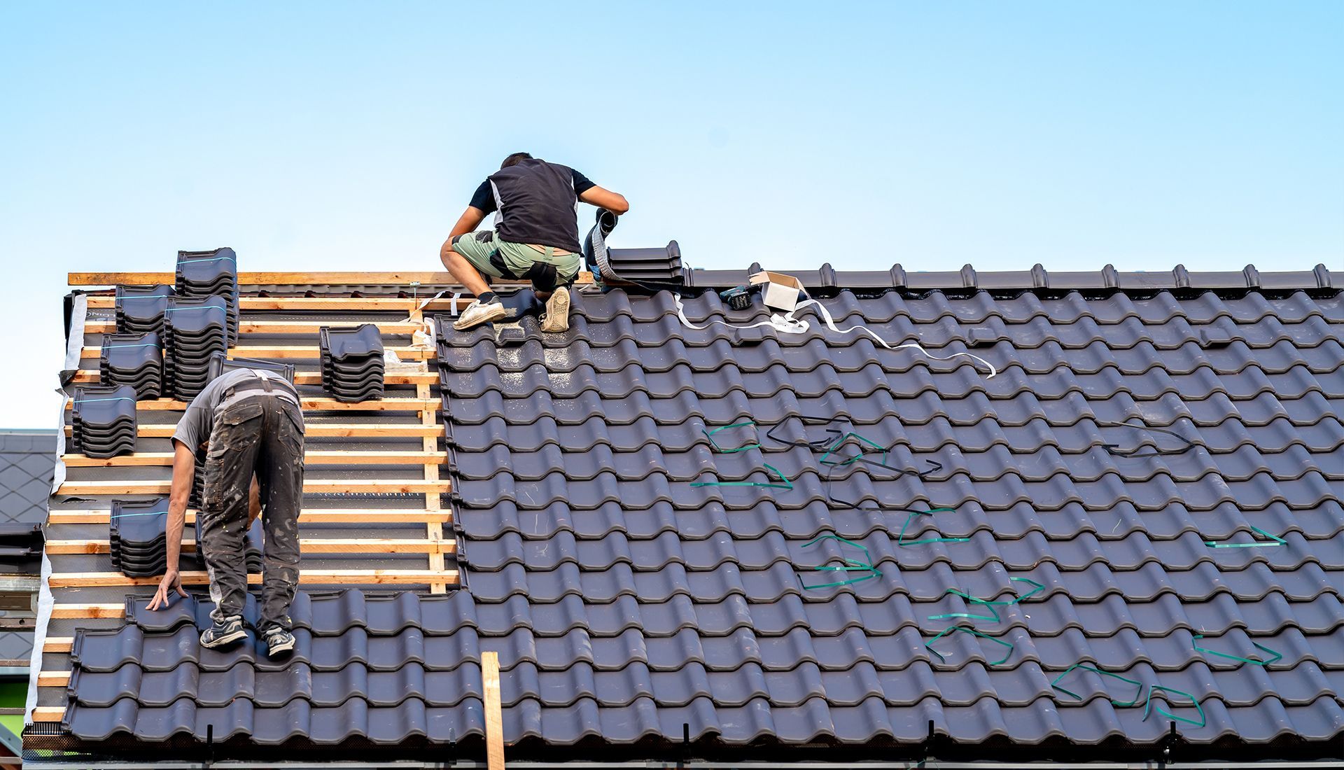 Two men are working on the roof of a house.