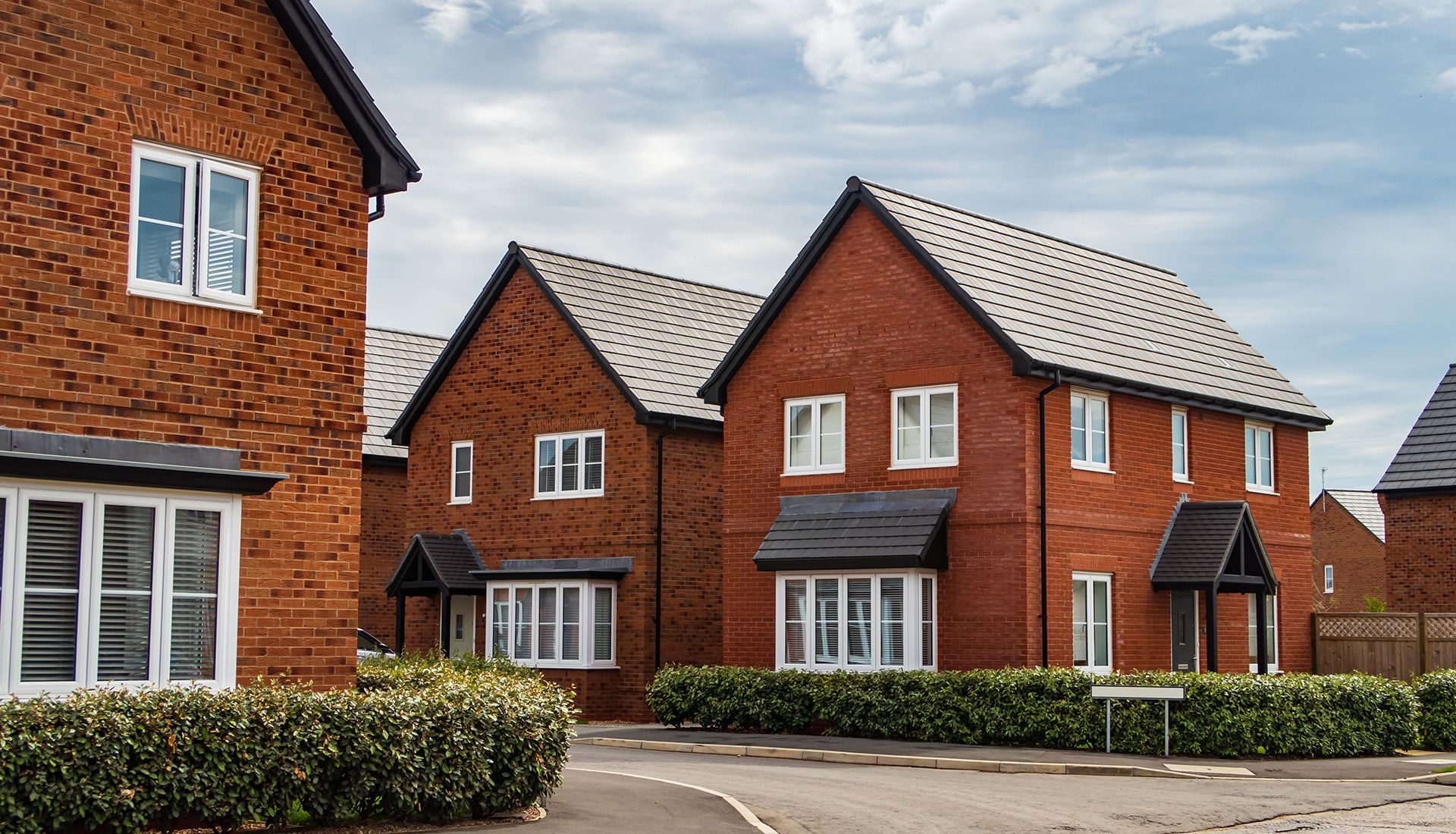 A row of red brick houses with white windows in a residential area.