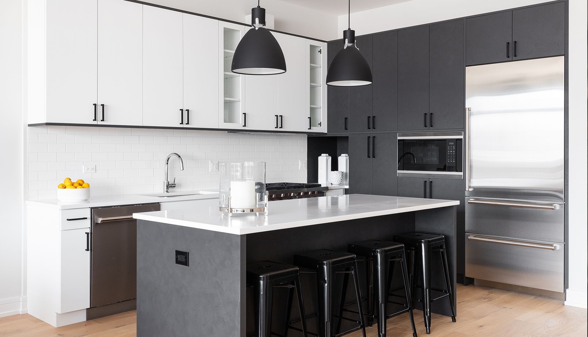 A kitchen with black cabinets and stools and a large island.
