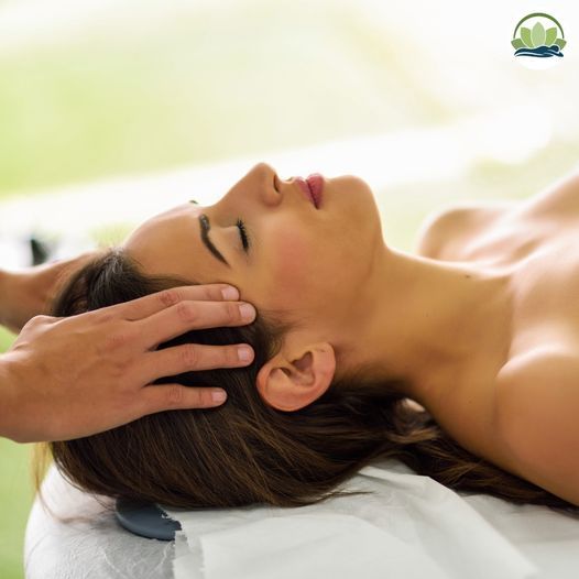 A woman laying on a bed getting a head massage
