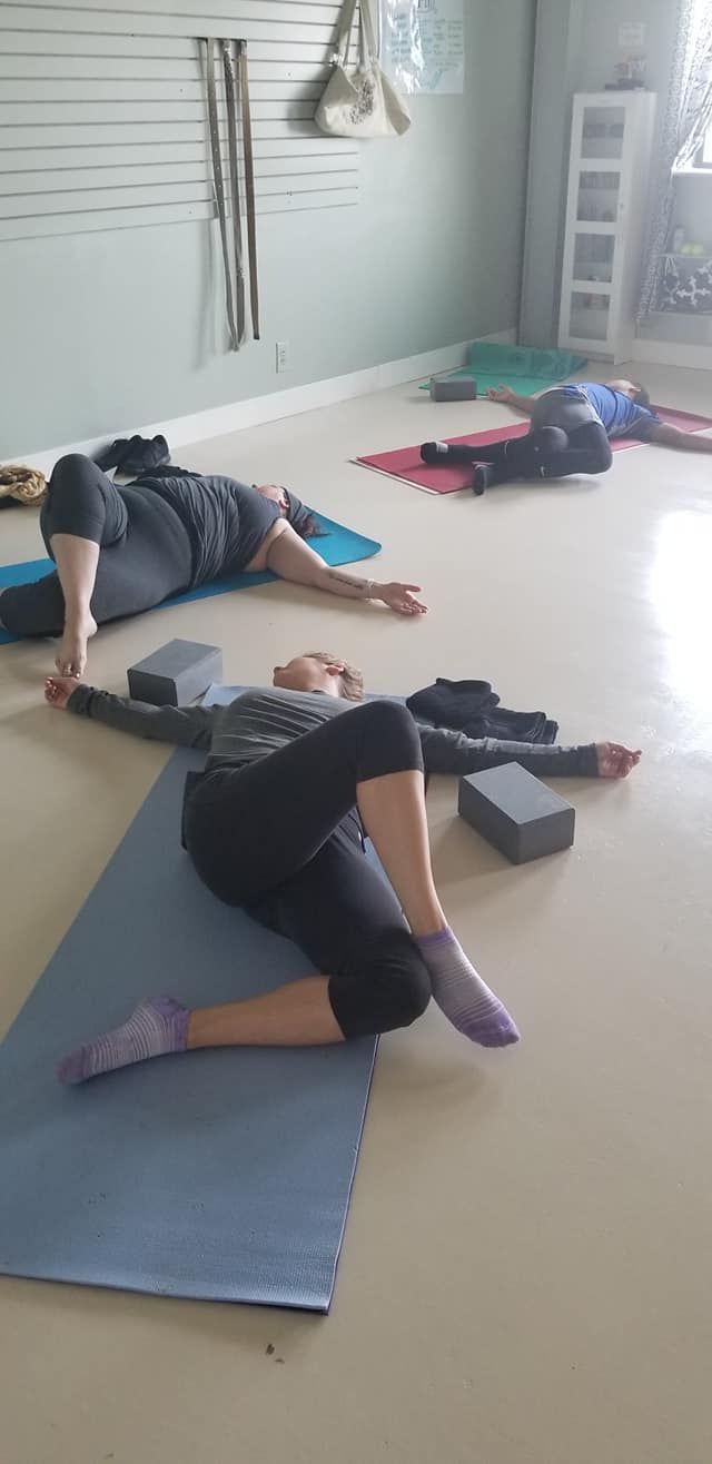 A group of people are laying on yoga mats in a room.