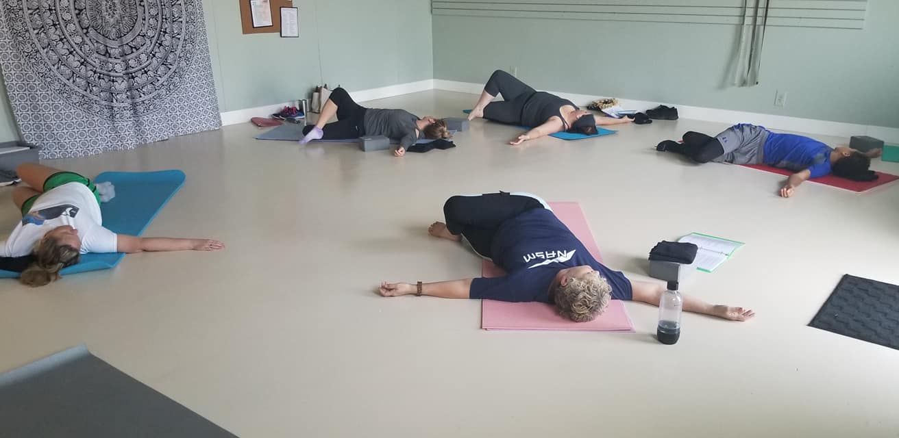 A group of people are laying on yoga mats in a room.