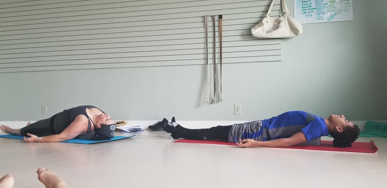 A man and a woman are laying on yoga mats in a room.