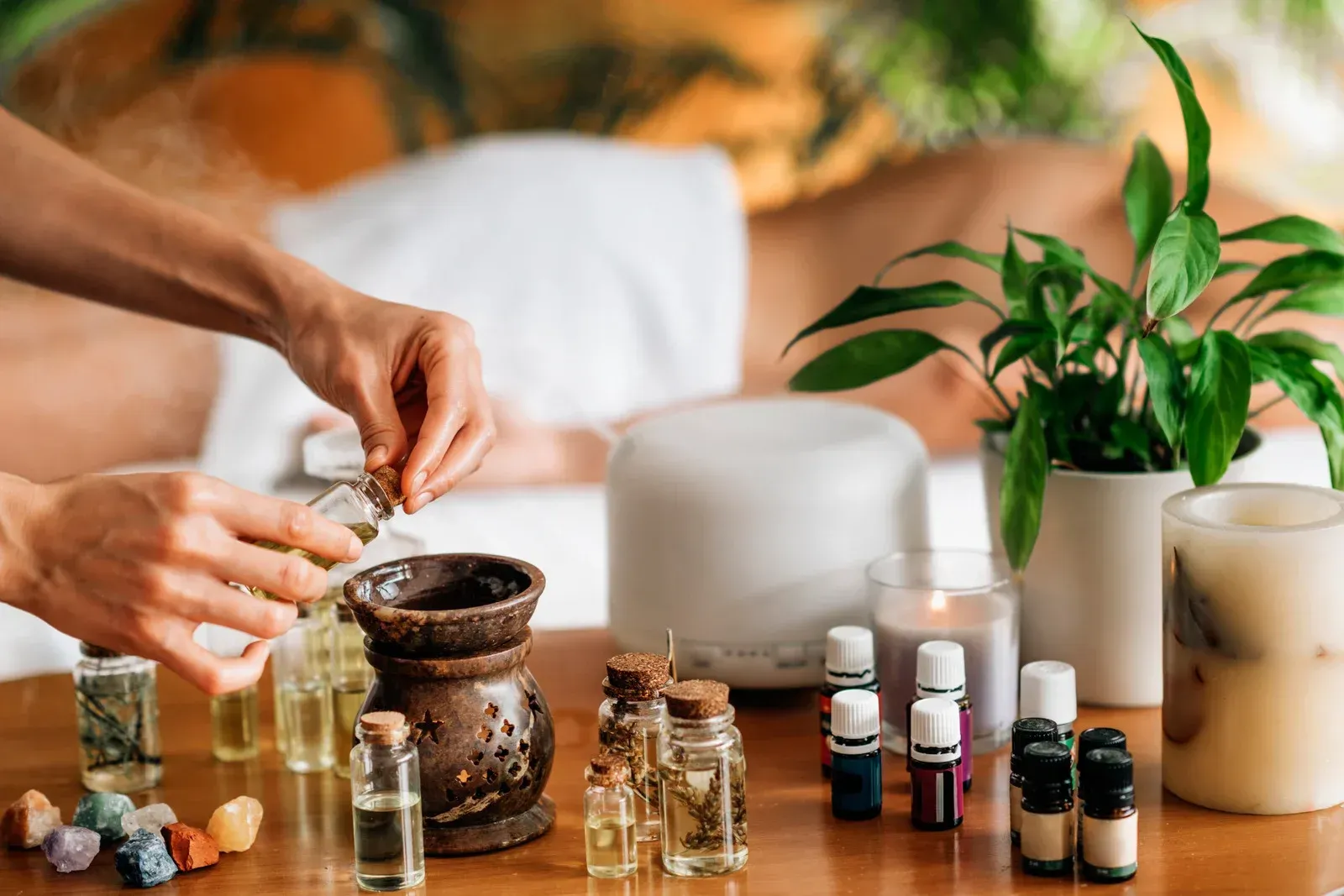 A person is pouring essential oil into a bottle on a table.