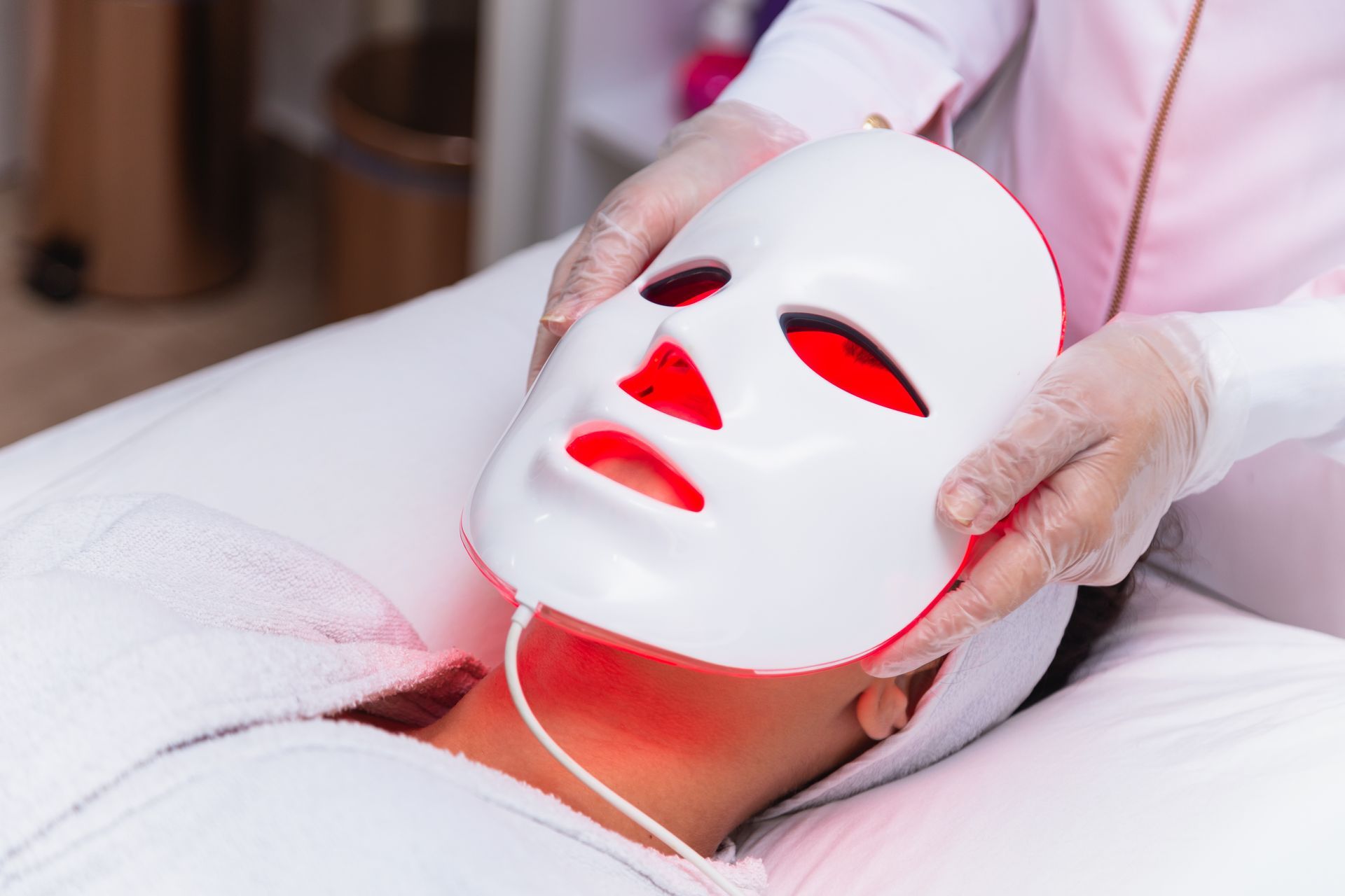 A woman is getting a led mask on her face.