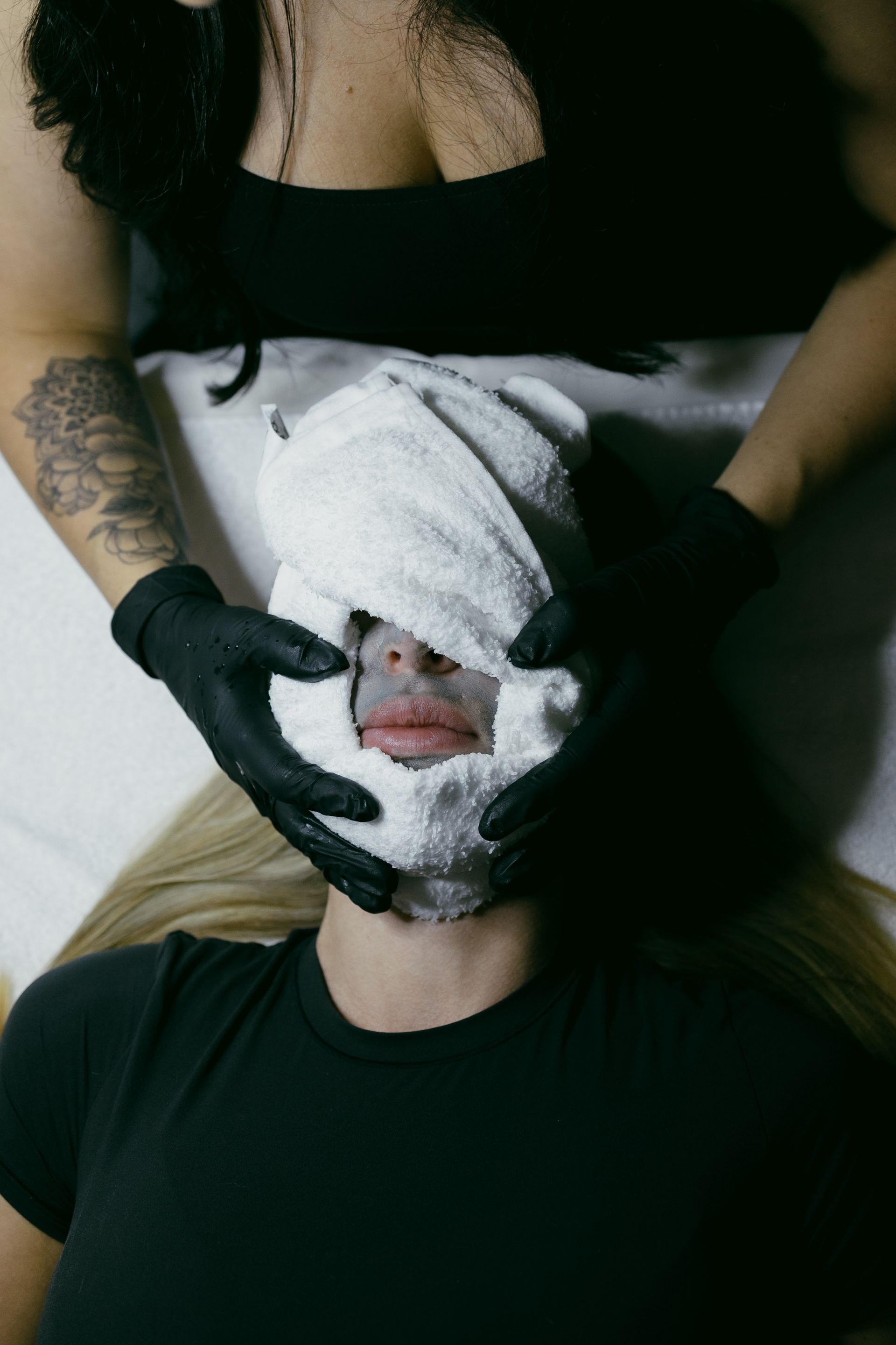 A woman is getting a facial treatment with a towel on her face.