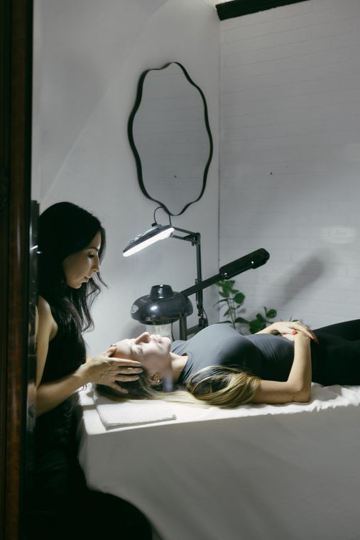 A woman is laying on a bed getting a facial treatment.