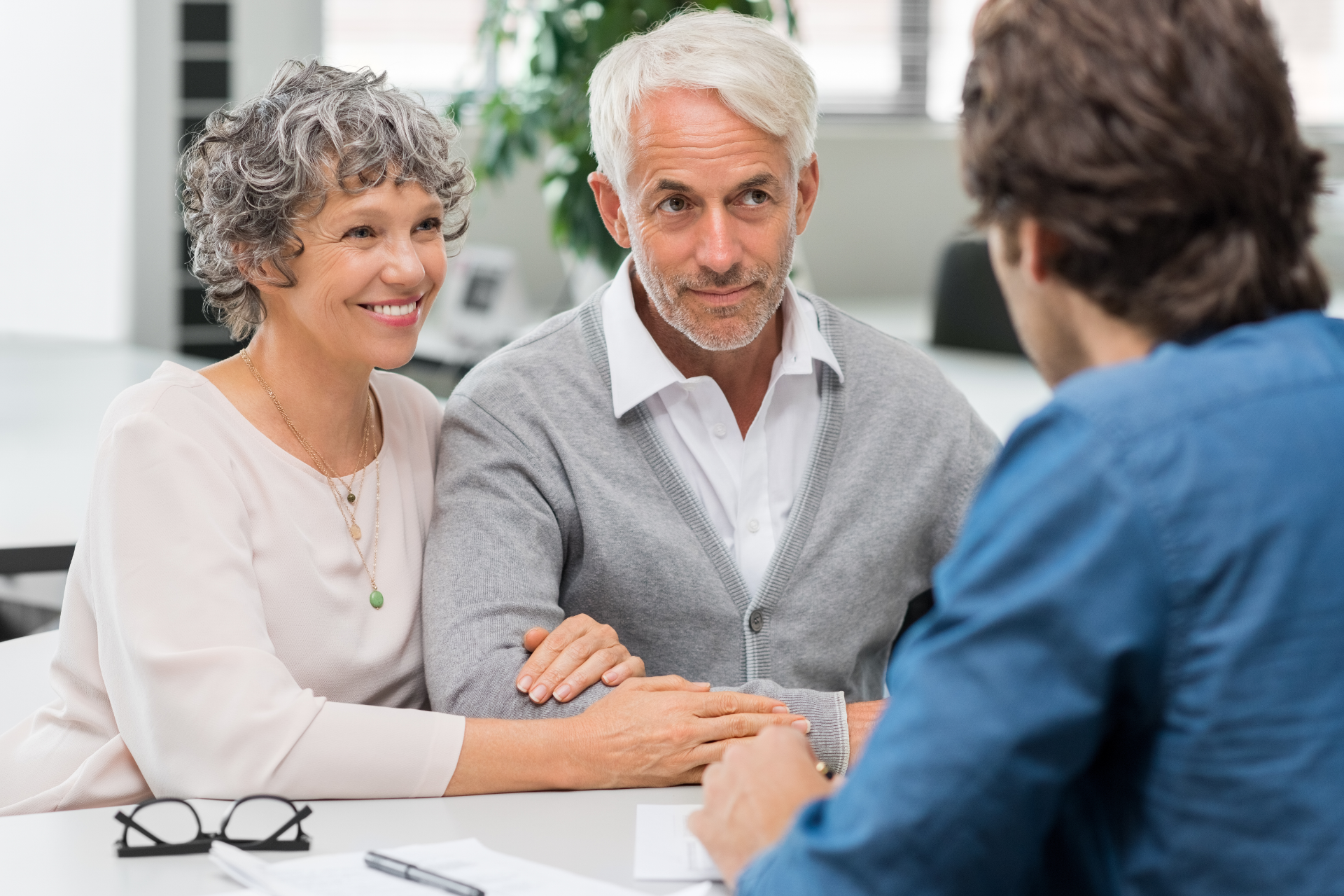 A couple consults with an advisor at a table; the woman smiles, and the man listens intently.