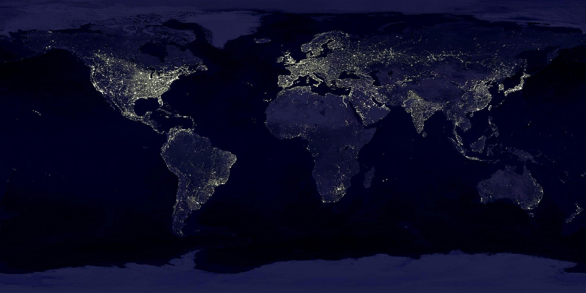 Nighttime view of Earth from space, showing city lights across continents.