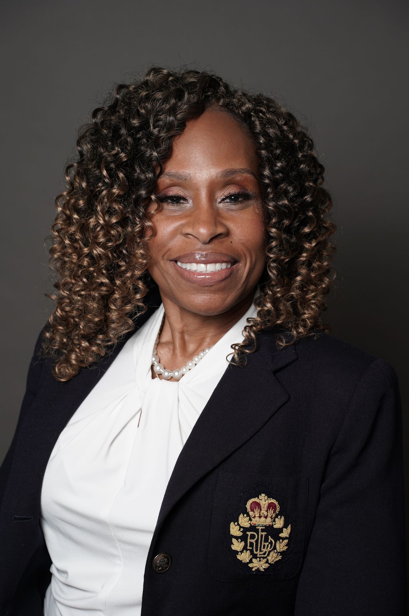 A woman is sitting at a desk with a laptop and a vase of flowers.