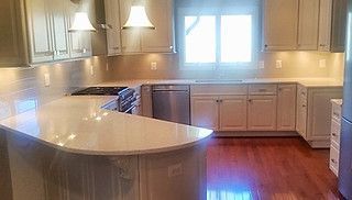A kitchen with white cabinets , stainless steel appliances , and hardwood floors.
