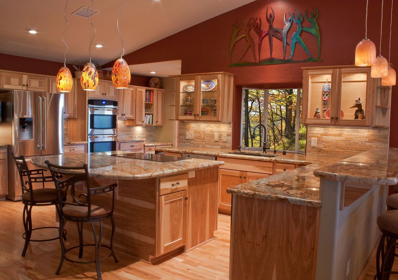 A kitchen with wooden cabinets , granite counter tops , stainless steel appliances and a large island.