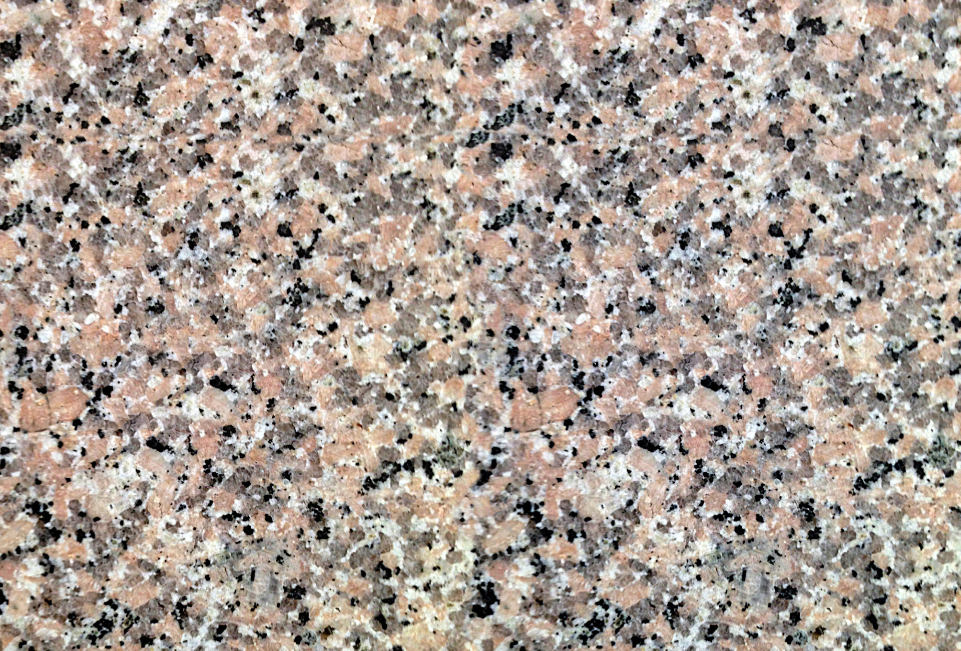 A close up of a pink granite counter top with black spots.