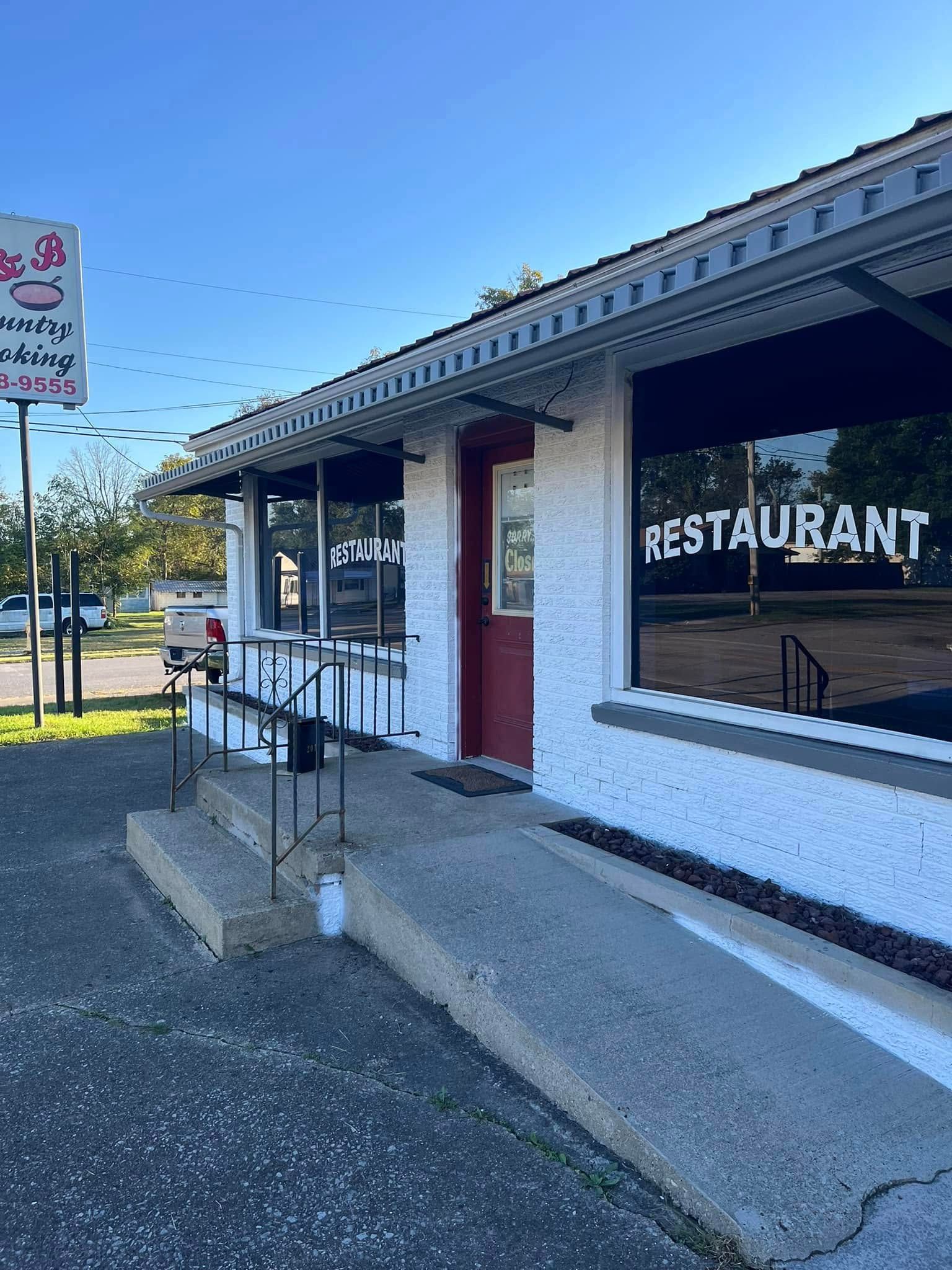 A white building with a red door and a sign that says `` restaurant ''.