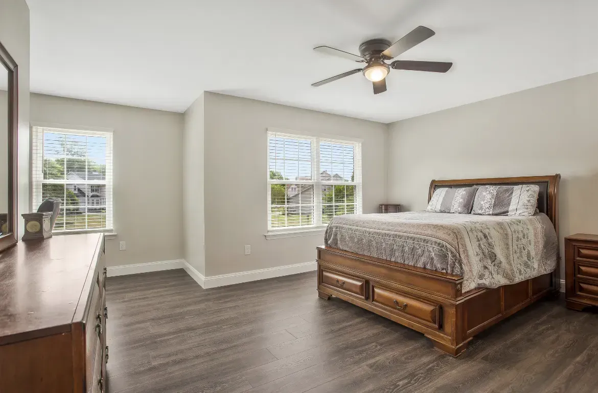 A bedroom with a bed , dresser , mirror and ceiling fan.