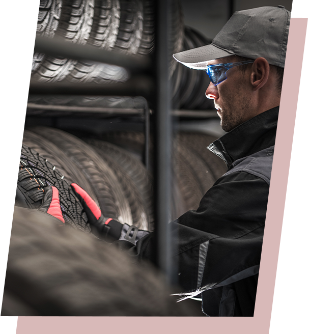 Person in work attire inspecting tires in a storage rack.