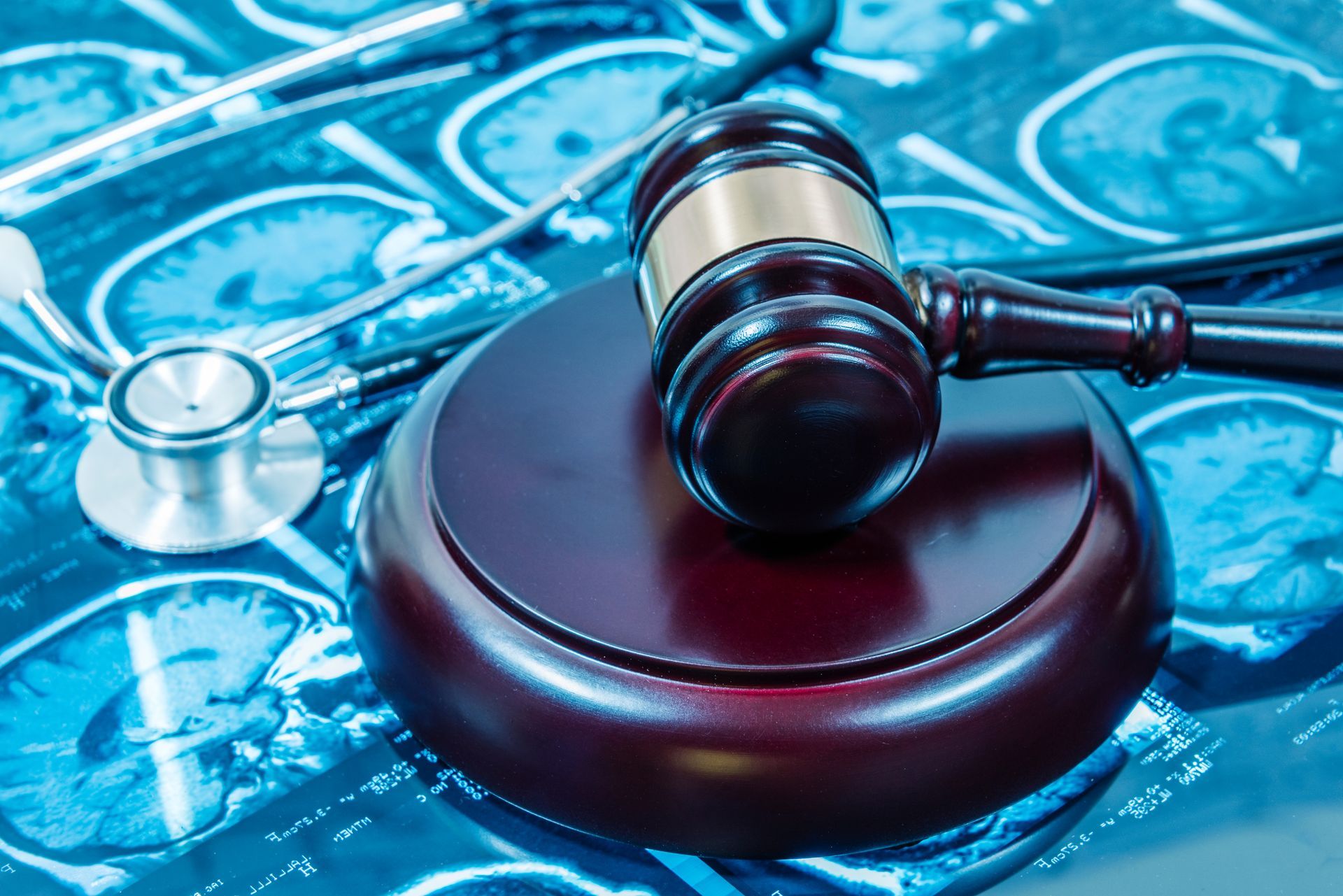 Gavel on a wooden block, stethoscope, and medical X-ray scans, all in a blue-toned setting.