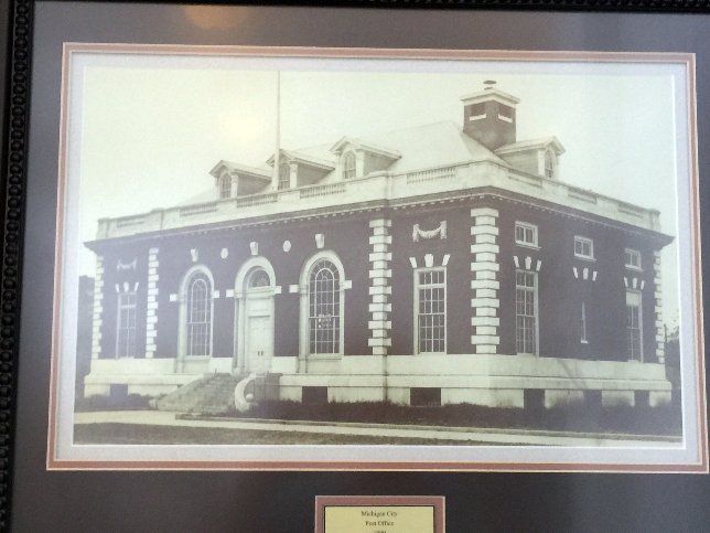 Framed, black and white photograph of a brick building with arched windows, possibly a historical post office.