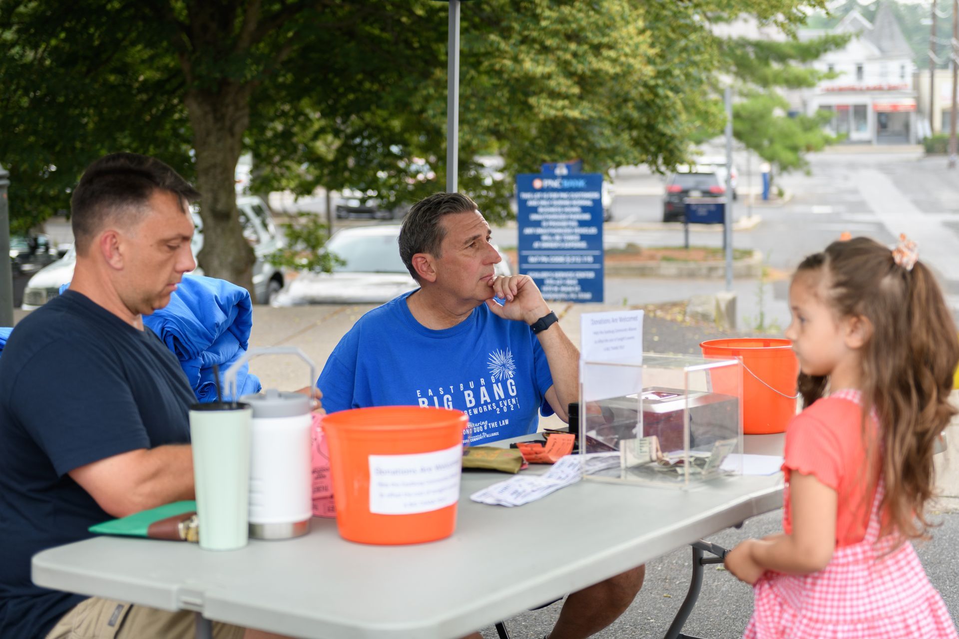 Two men and a little girl are sitting at a table.