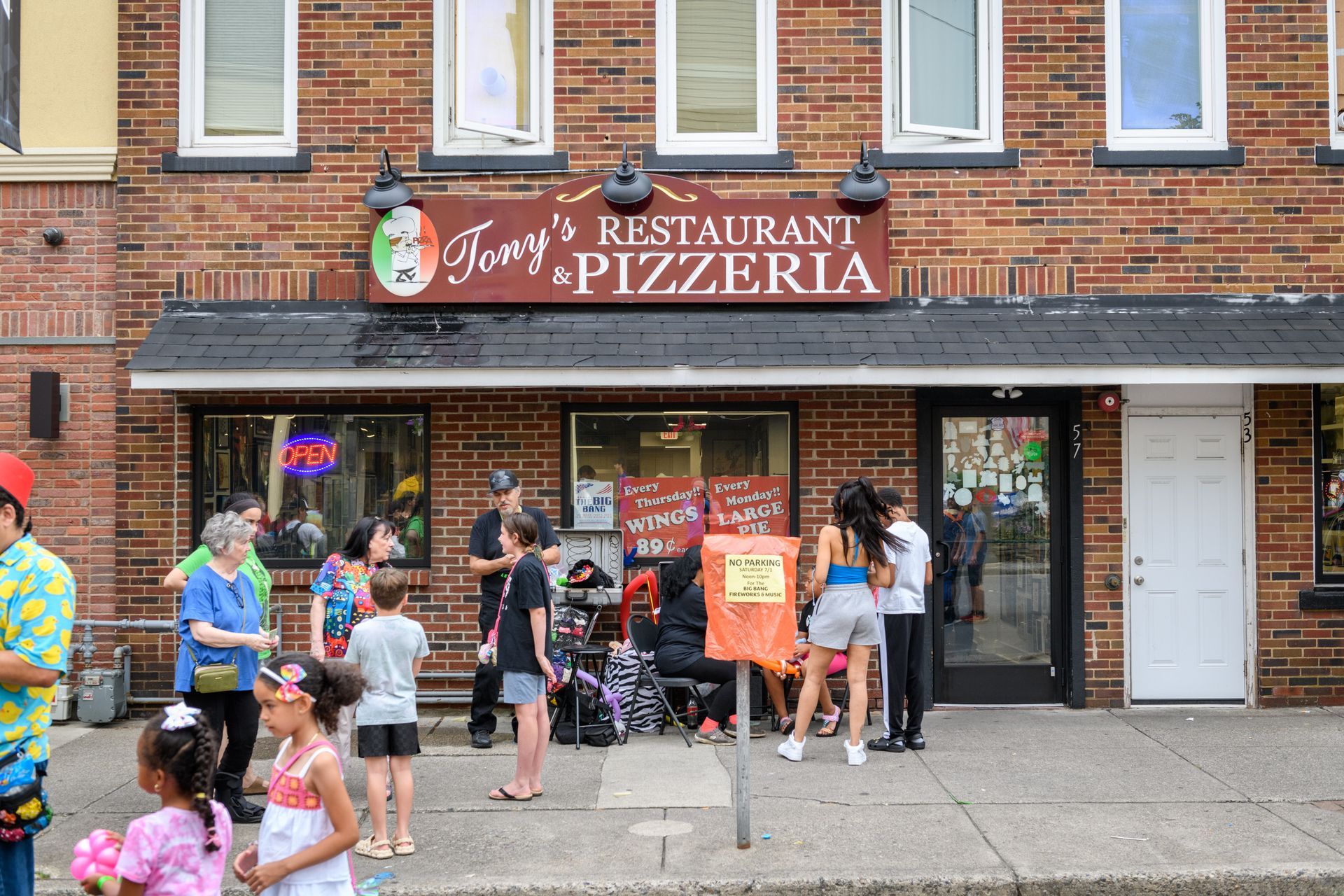 A group of people are standing outside of a pizzeria.