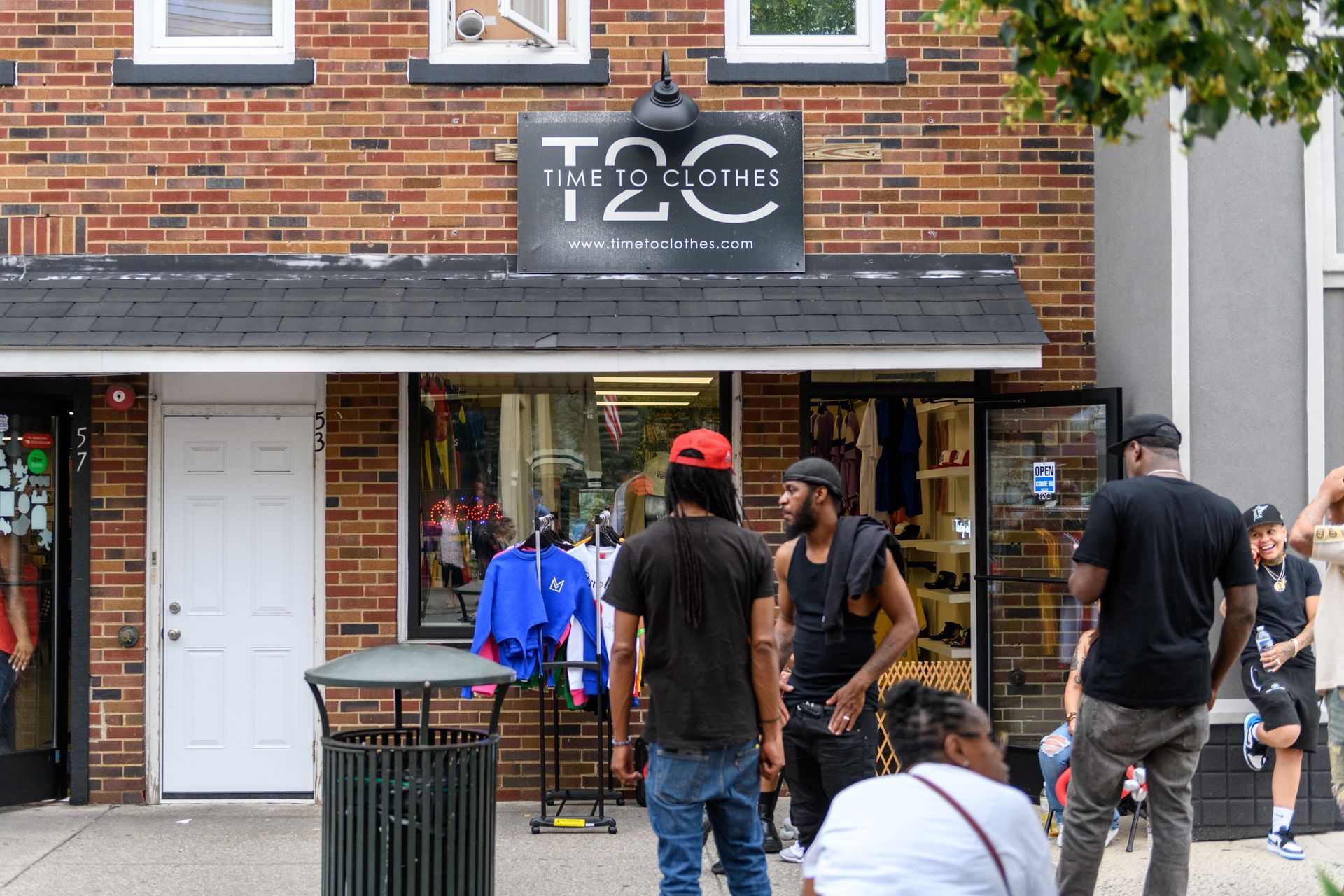 A group of people are standing outside of a store called t2c.