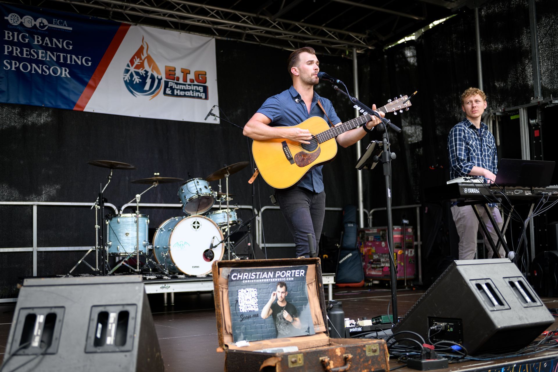 A man is playing a guitar on a stage in front of a sign that says big bang presenting sponsor