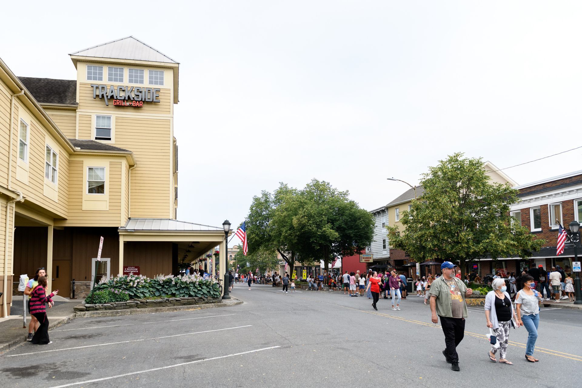 A group of people are walking down a street in front of a building that says ' princess ' on it