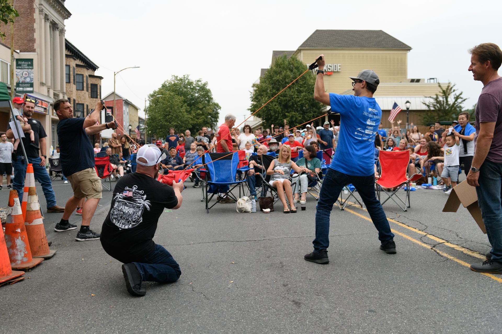 A man in a blue shirt is kneeling down in front of a crowd of people.