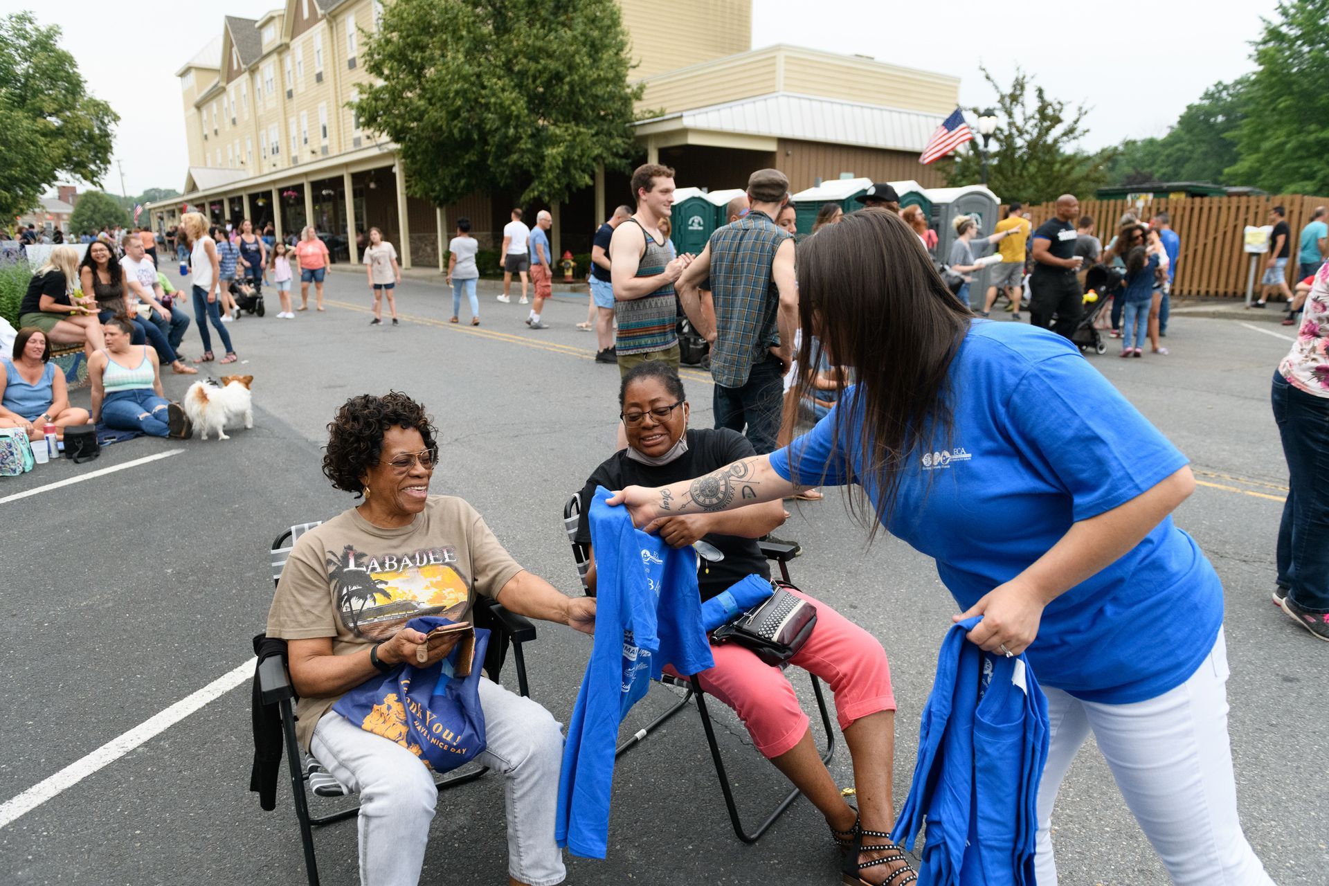 A woman in a blue shirt is talking to two women in chairs