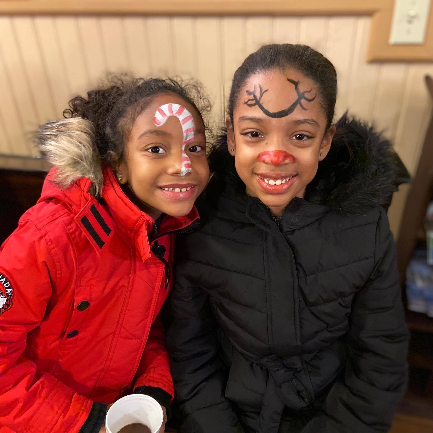 Two young girls with candy canes painted on their faces