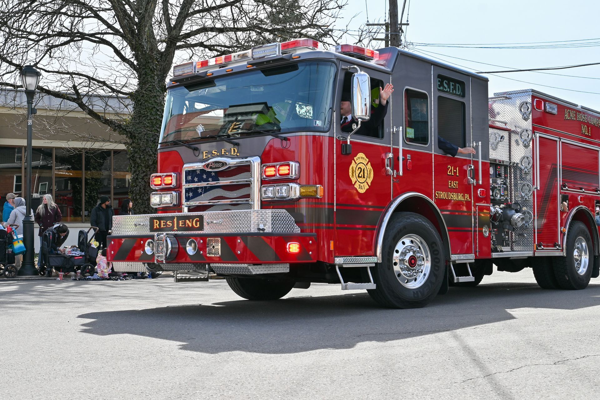 A red fire truck is driving down a street in a parade.
