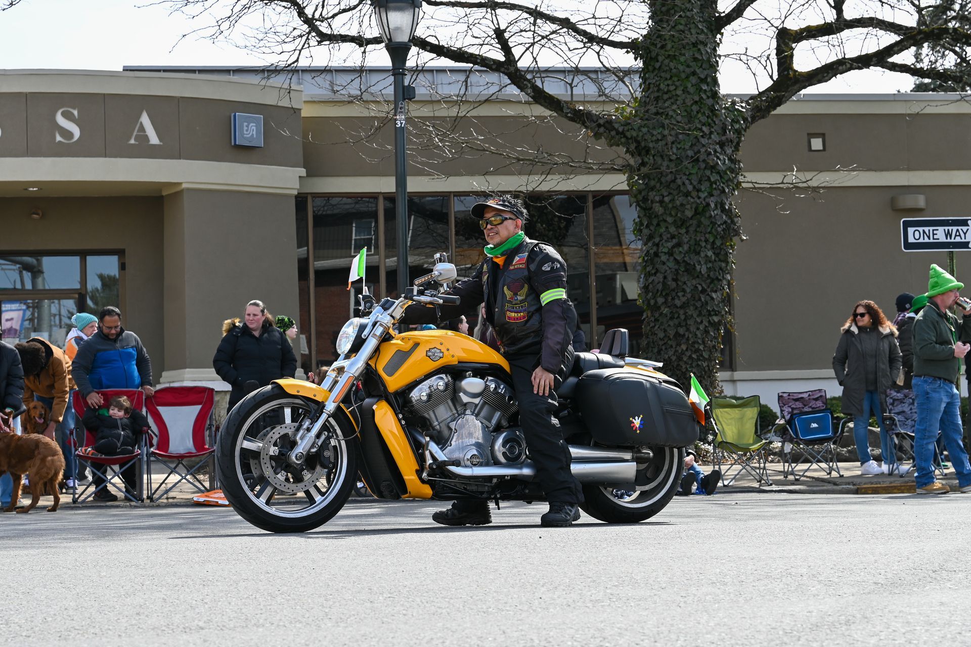 A man is riding a yellow motorcycle down a street.