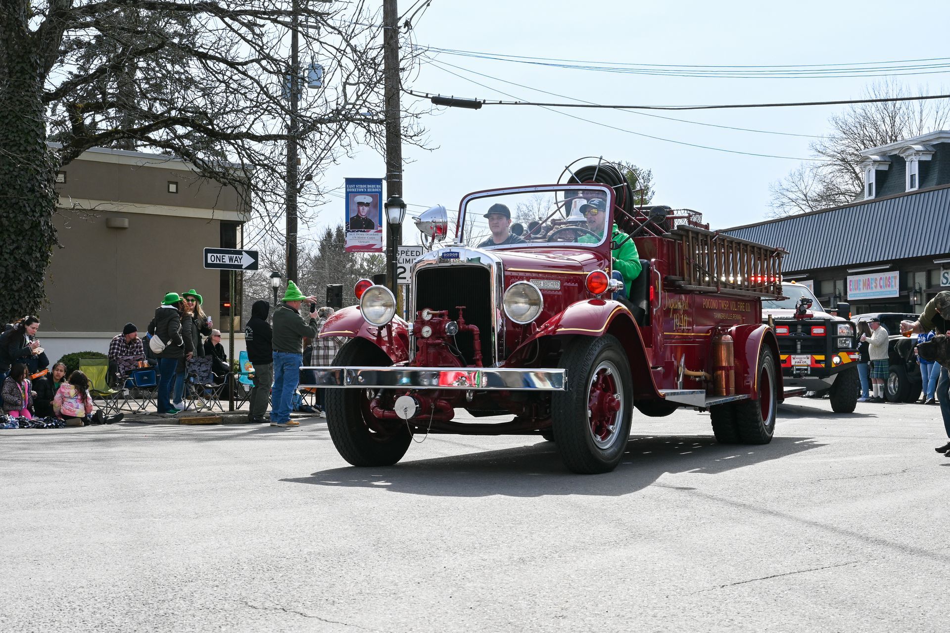 An old red fire truck is driving down the street in a parade.