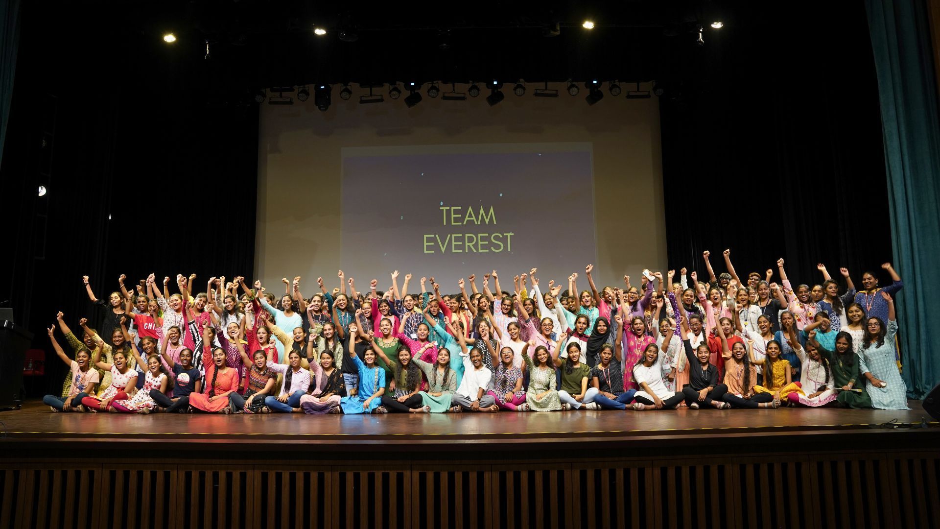A large group of people are posing for a picture on a stage.