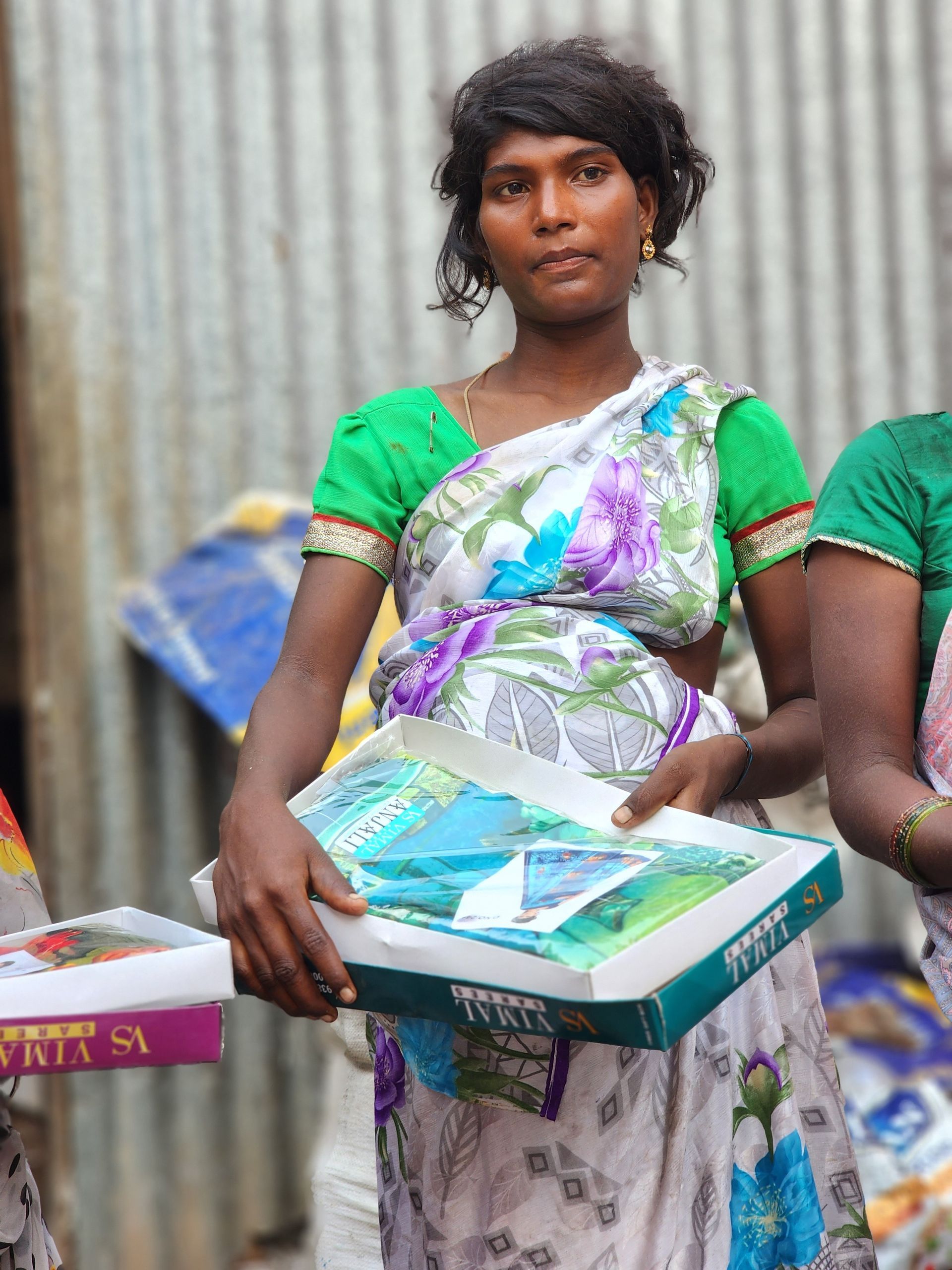 A woman in a green top is holding a box that says ' fruit sa ' on it