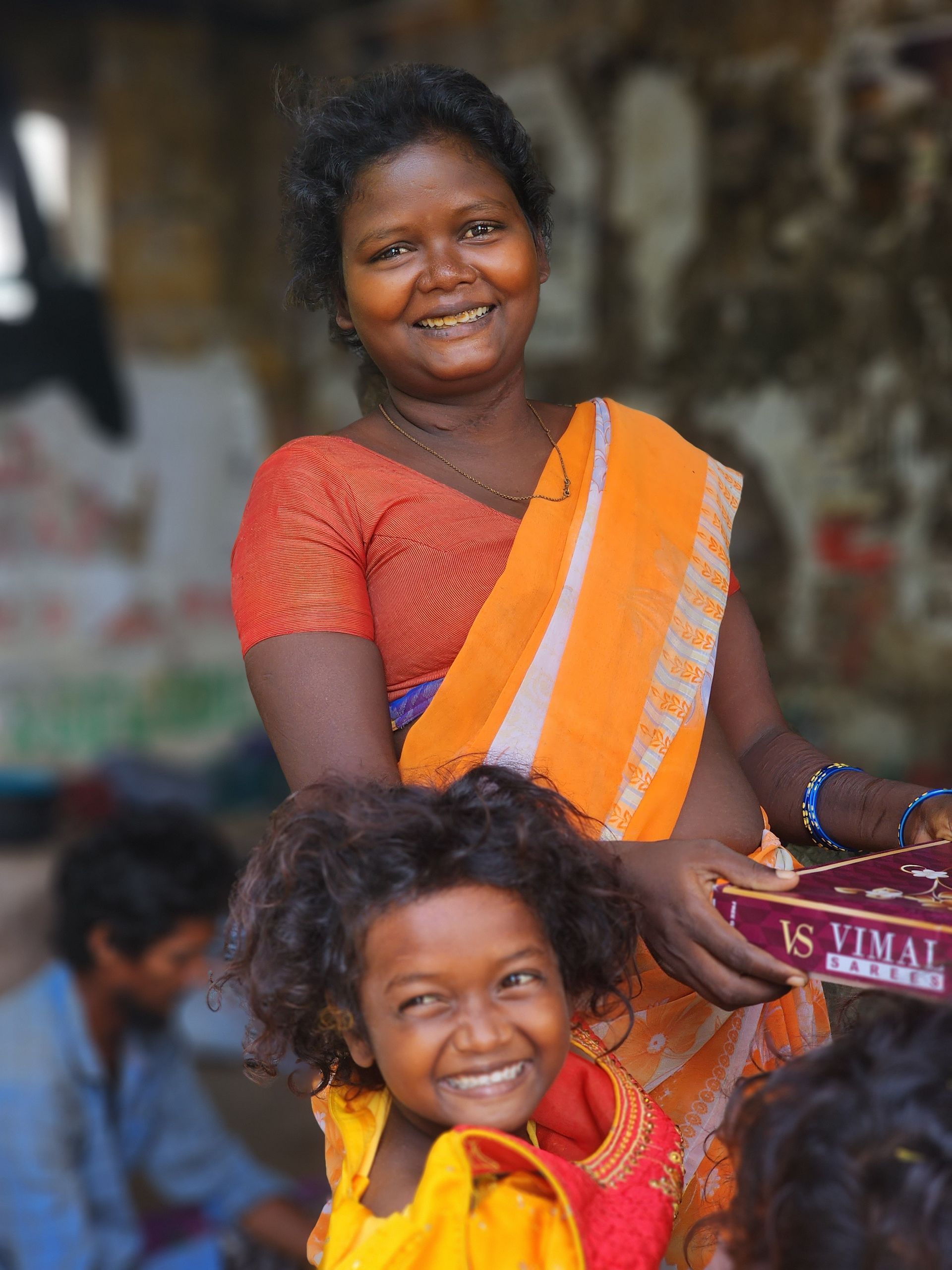 A woman is holding a little girl on her shoulders and smiling
