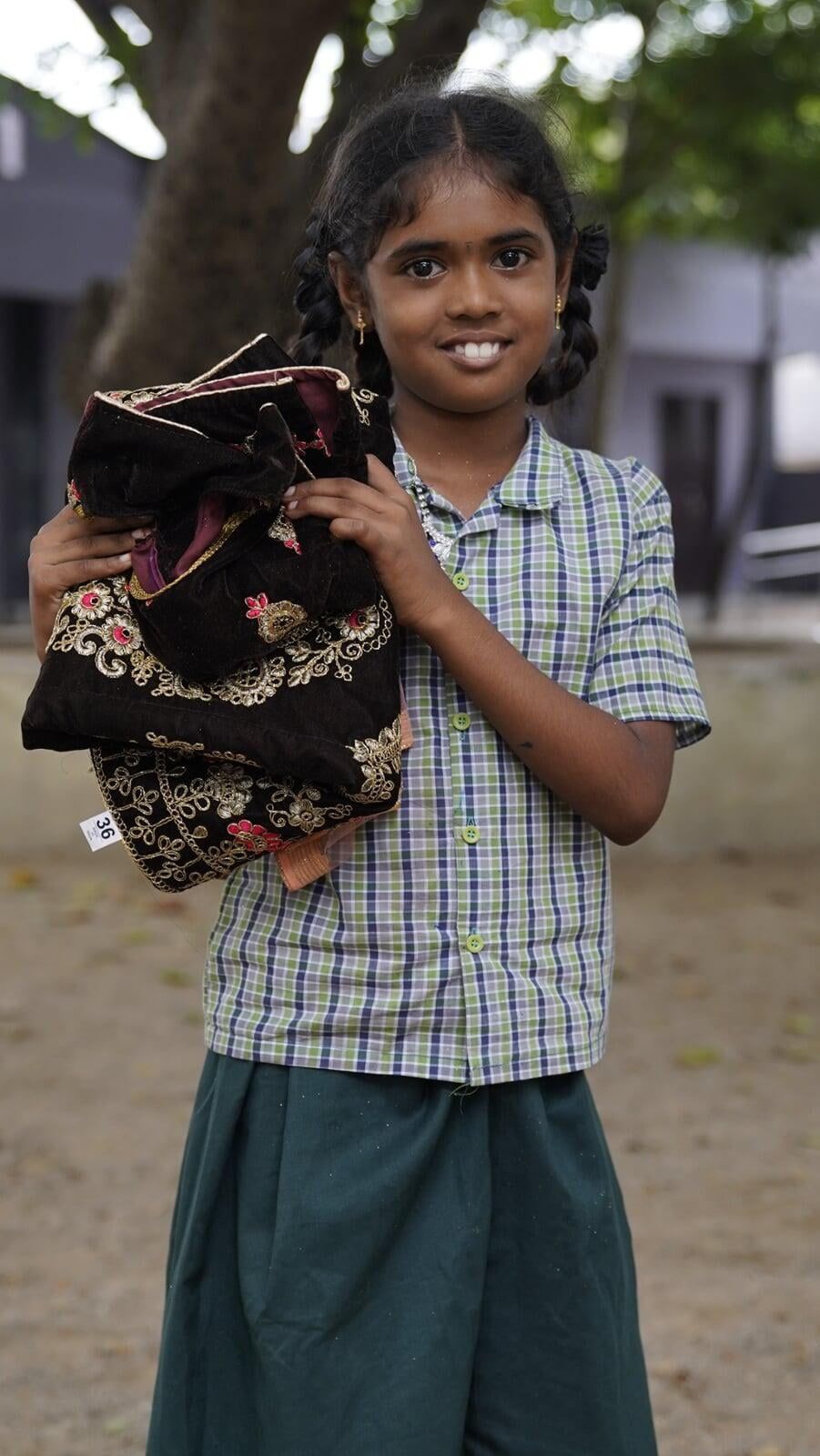 A young girl in a plaid shirt is holding a blanket in her hands.