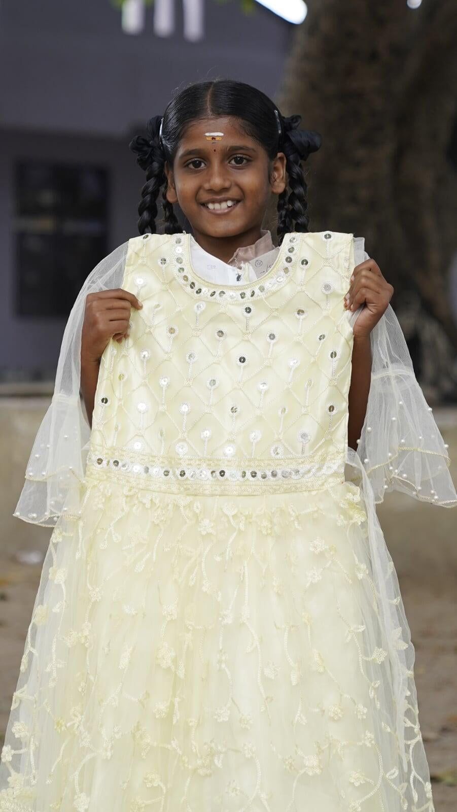 A little girl is holding a white dress in her hands.