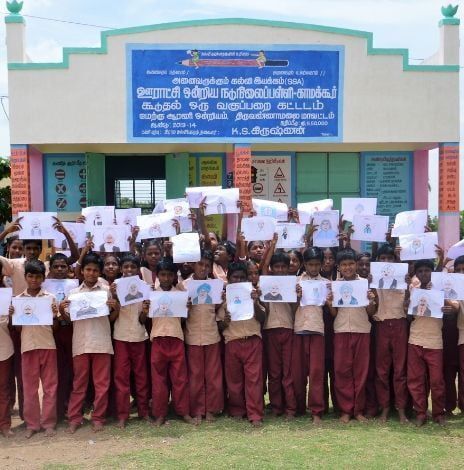 Students in school holding pictures that they drew