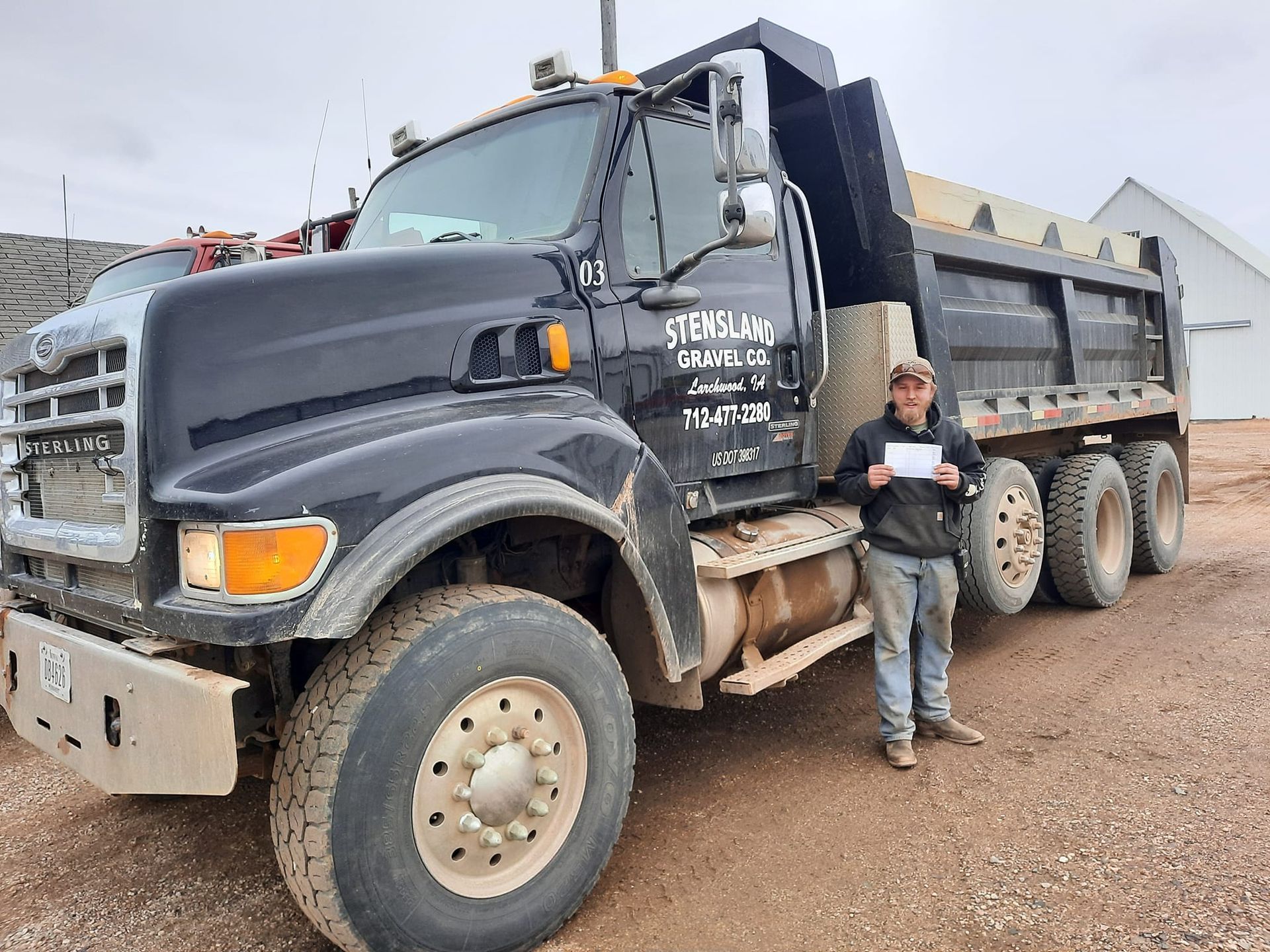 A man is standing in front of a dump truck.