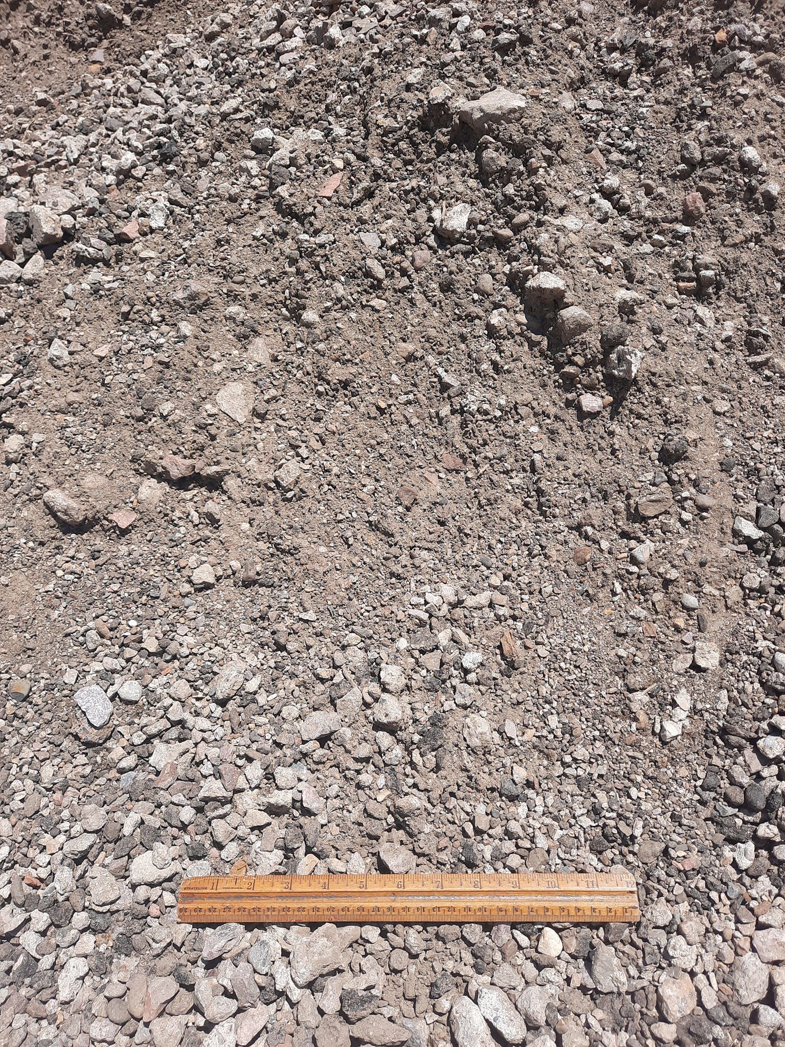 A ruler is sitting on top of a pile of gravel.