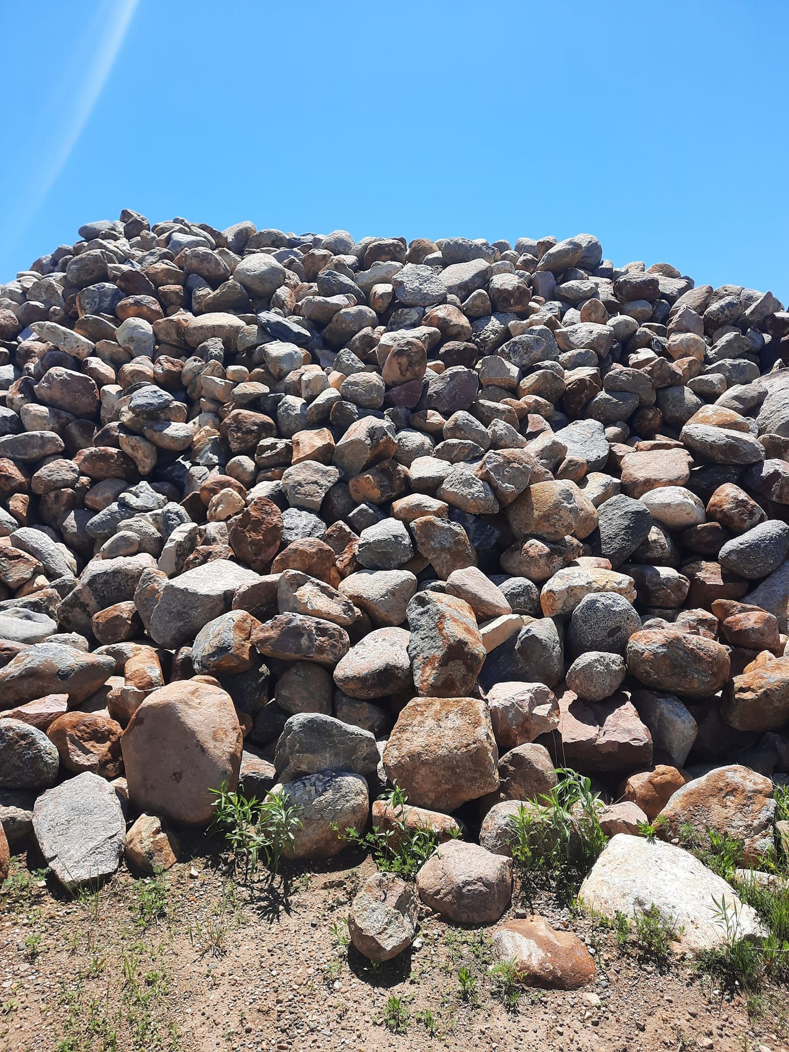 A large pile of rocks is sitting on top of a dirt field.