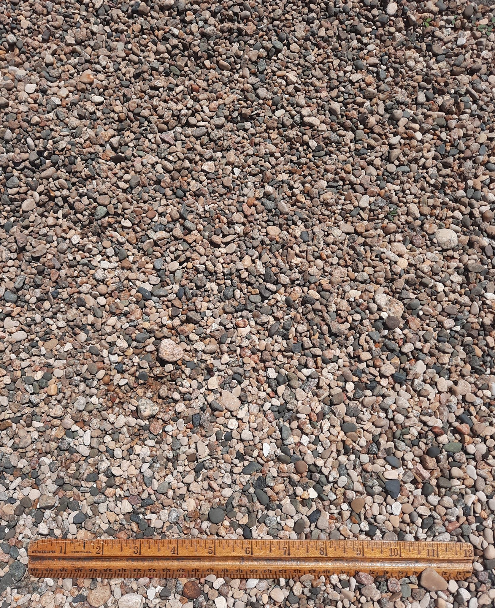 A ruler is laying on top of a pile of gravel.