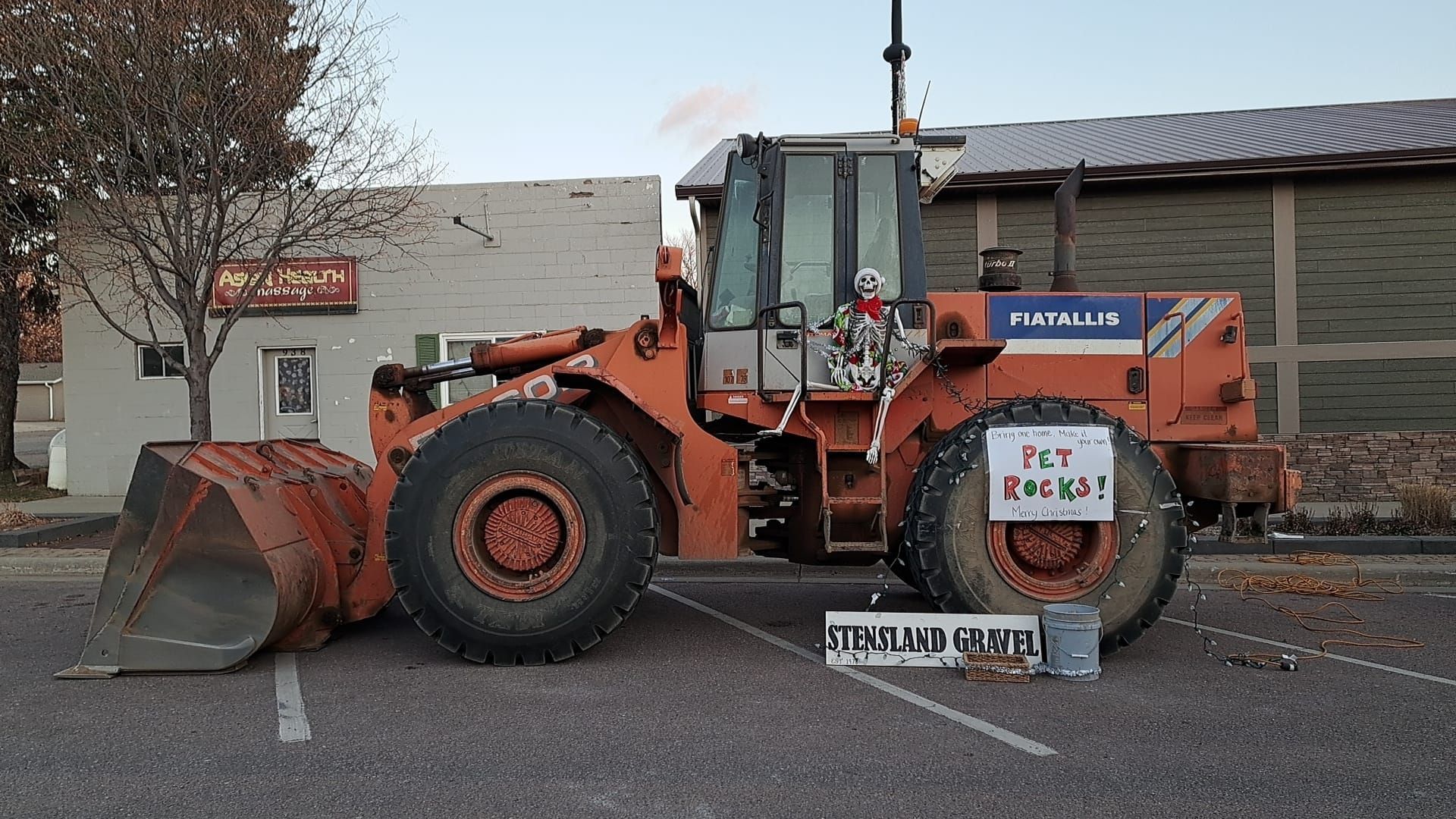 A large orange bulldozer is parked in a parking lot