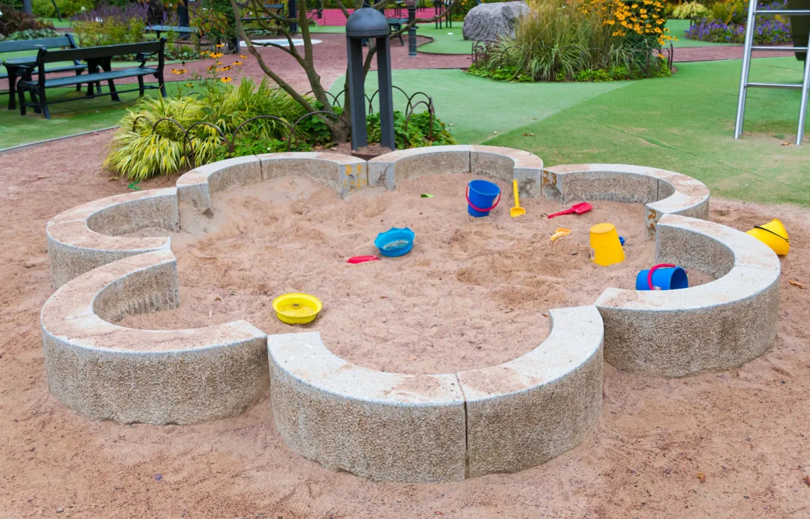 A sandbox in the shape of a flower with toys in it.