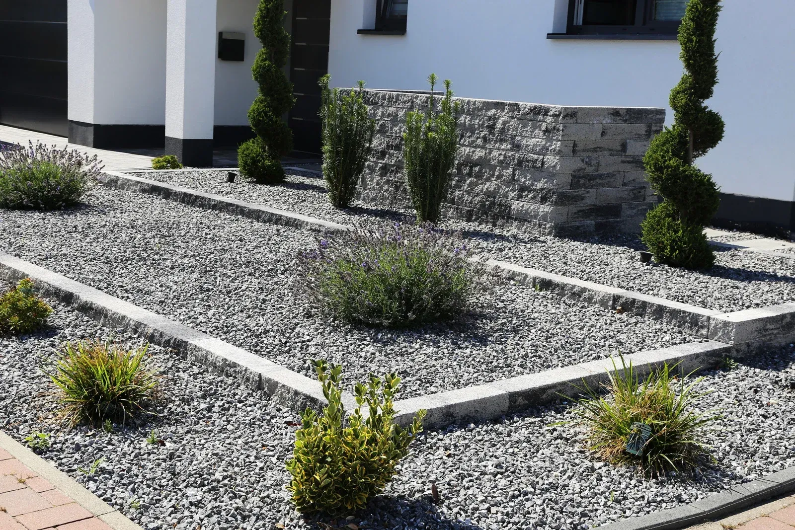 A garden with gravel and plants in front of a house.