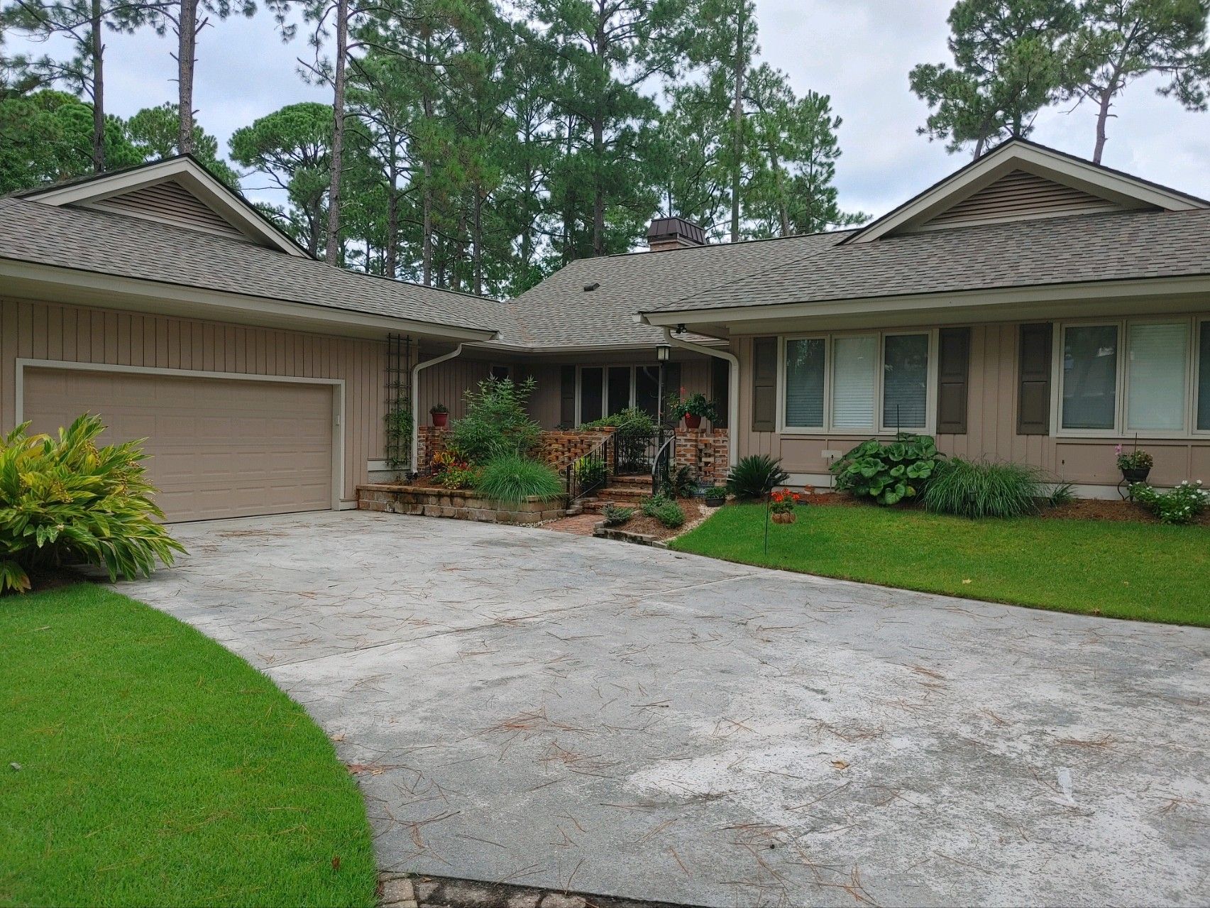 A house with a driveway and a garage is surrounded by trees.