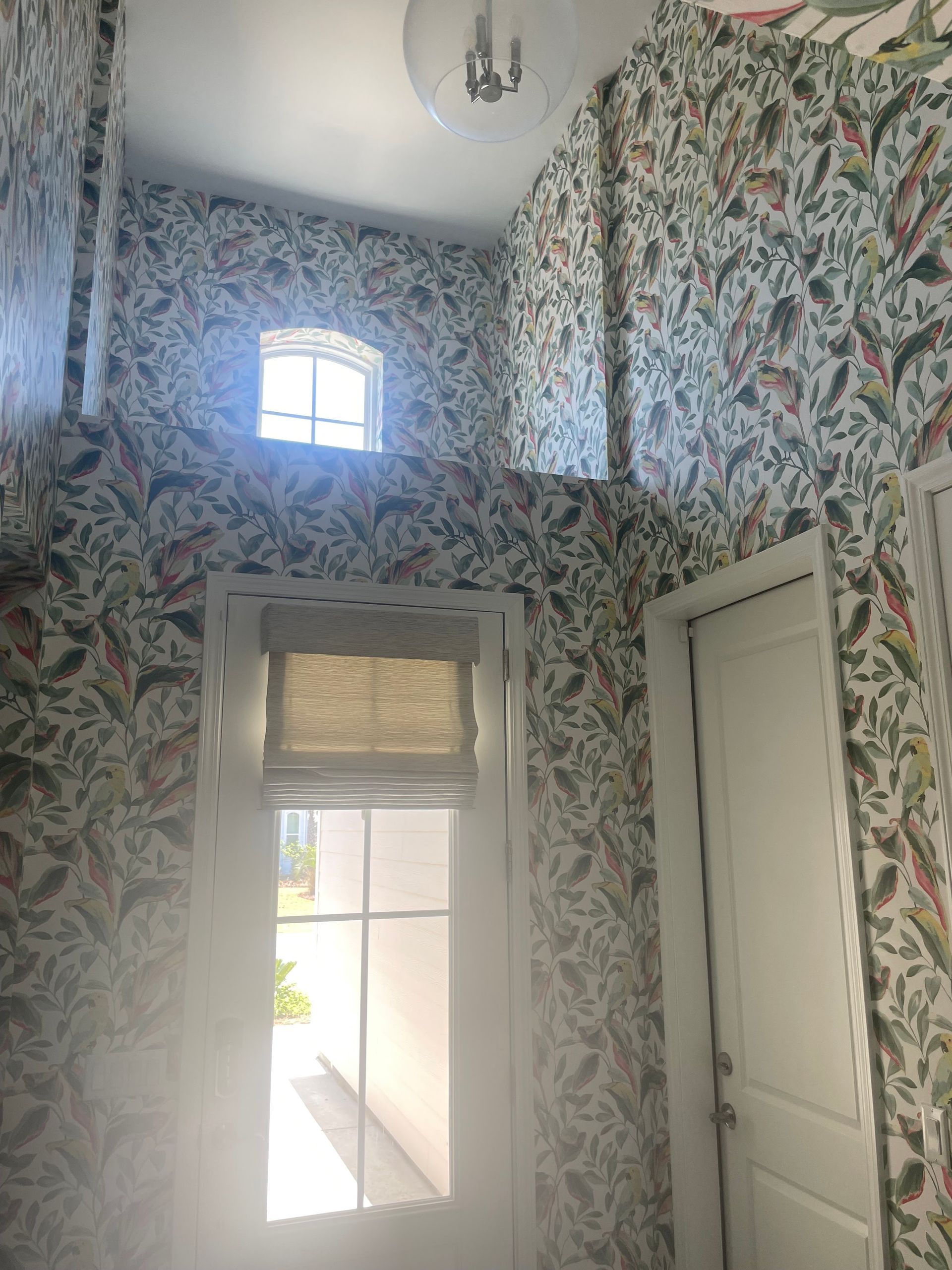 A hallway with floral wallpaper and a window.