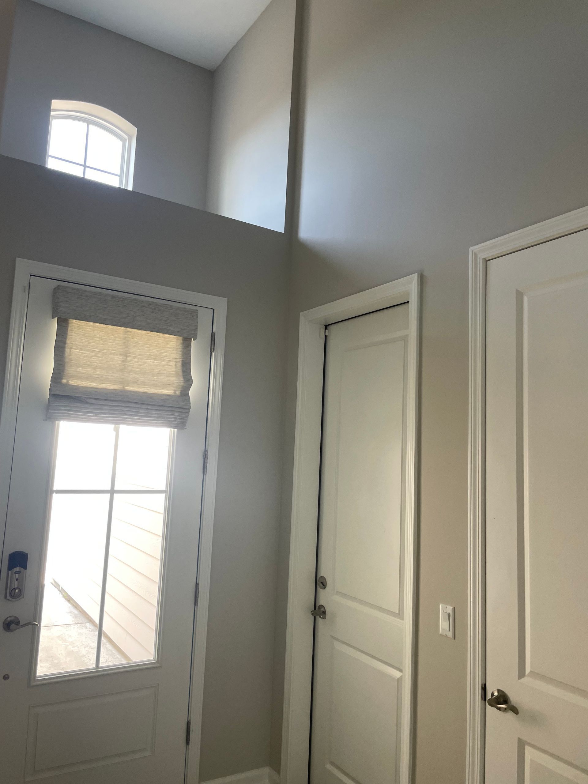 A hallway with white doors and a window