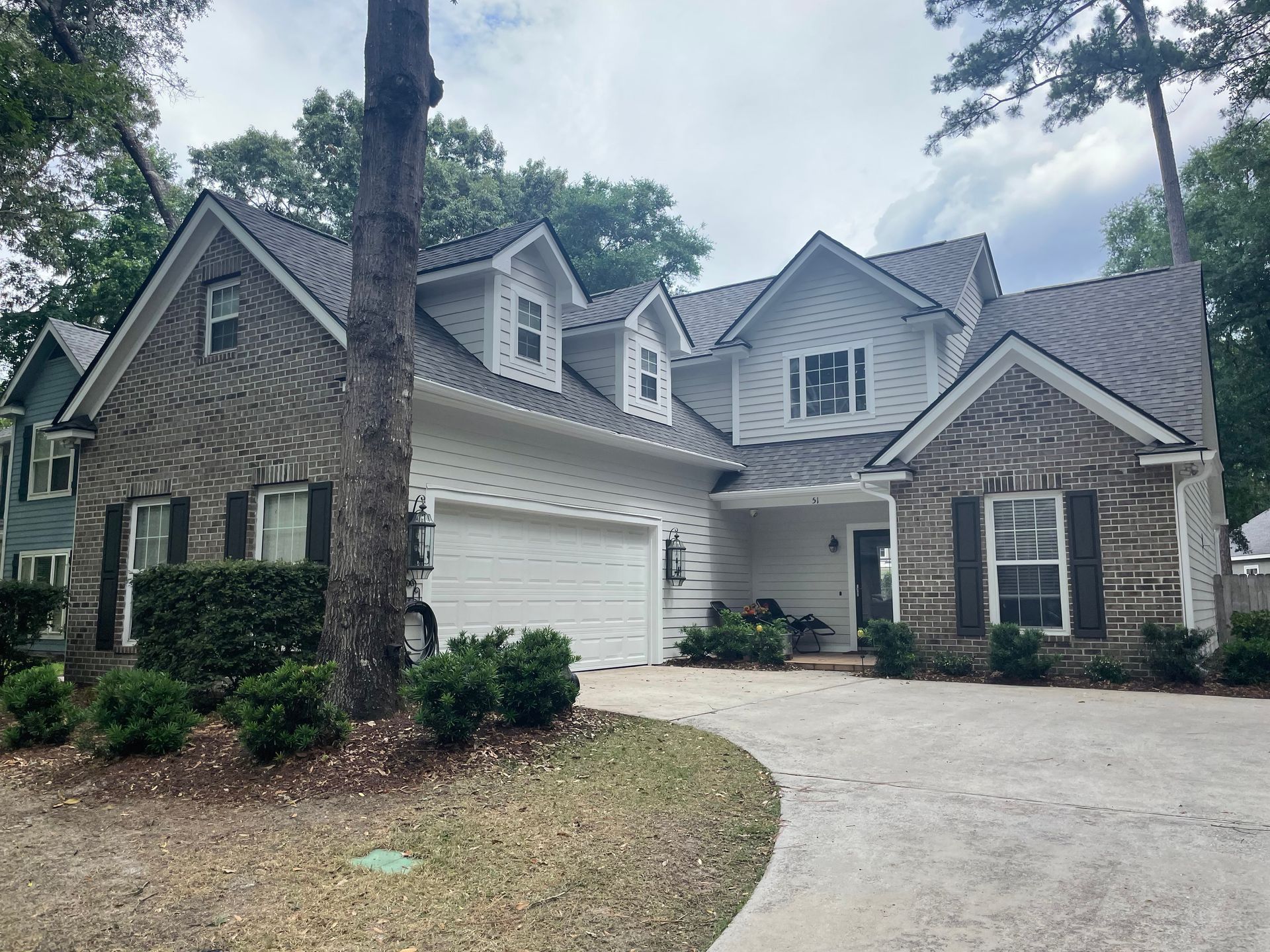 A large brick house with a white garage door and black shutters